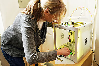 Foto einer Mitarbeiterin beim 3-D-Drucker