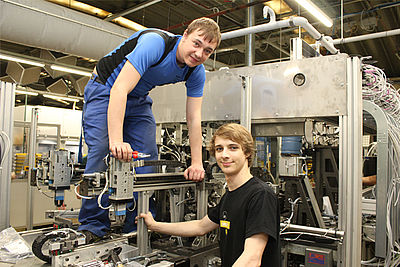 Photo of employees servicing a production machine 